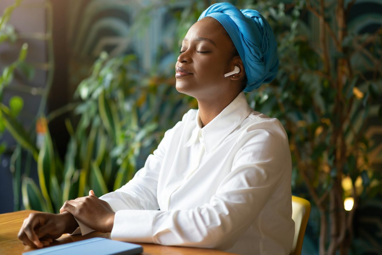 peaceful young black woman listening to music at cafe.jpg